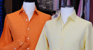 Two button-up shirts, one orange and one yellow, on mannequins.
