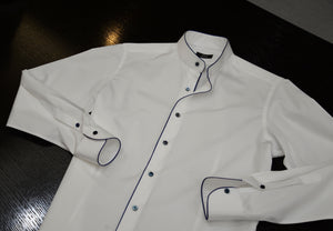 A white Anto band collar shirt laid flat on a surface showcasing the blue piping detail. 