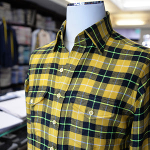A yellow, black and green flannel check sport shirt with two pockets, showcased on a mannequin.